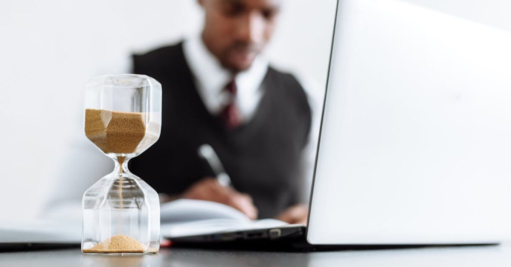 Businessman at desk with hourglass indicating time management and daily work routine.