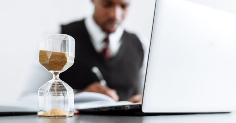 Businessman at desk with hourglass indicating time management and daily work routine.
