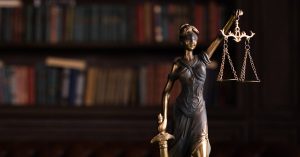 Lady Justice and gavel on a table in a classic law library setting.
